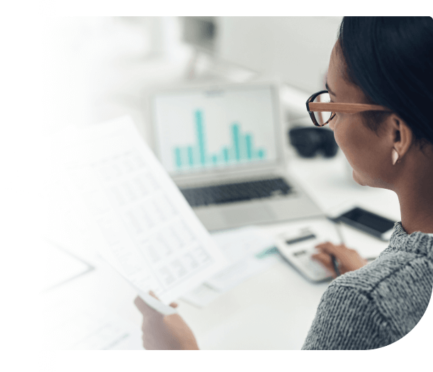 woman at laptop with paper and calculator reviewing accounts payable