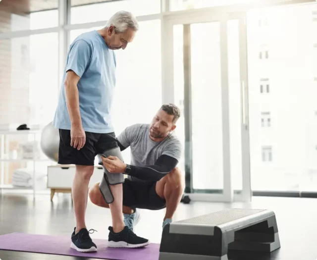 man performing physical therapy with senior male patient